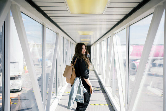 Smiling woman with backpack standing in airport jetway