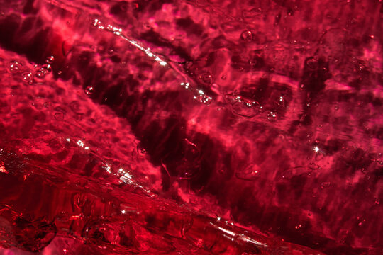 Vibrant red liquid with bubbles. Abstract cosmetic textured background
