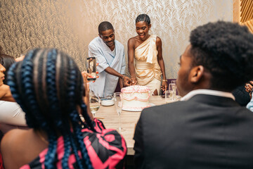 Couple cutting cake during celebration with friends