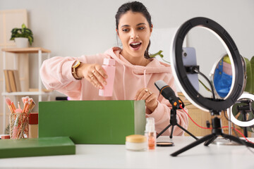 Female beauty blogger with perfume recording video at home