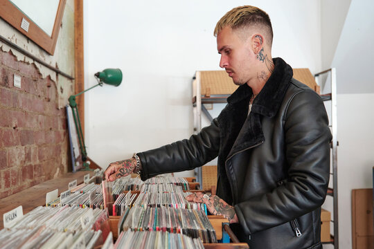 Person browsing through vinyl records at a local music store