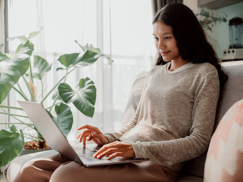 Woman Relaxing on Couch Working on Laptop from Home