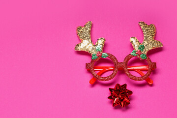Reindeer face made of horns with eyeglasses and Christmas ball on pink background