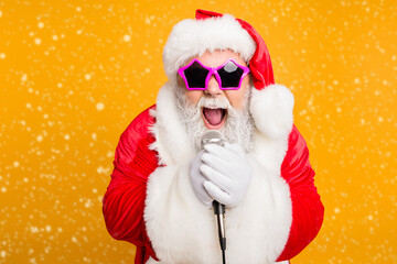 Jolly christmas x-mas performance from funky santa claus Modern crazy grandfather in red fairy north-pole creature costume sing song on stage hold microphone scream isolated yellow color background