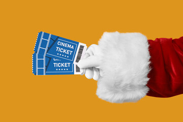 Santa's hand with cinema tickets on yellow background
