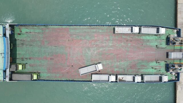 top down view truck loading into a car carrier ship. Car ferry leaving docks fully loaded.