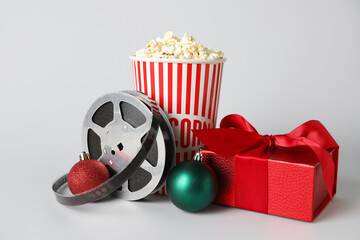 Bucket of popcorn, film reel, gift box and Christmas balls on white background
