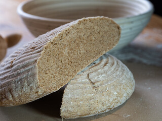 Handmade bread baked to the stone with mould of wicker and bakery utensils on wooden table