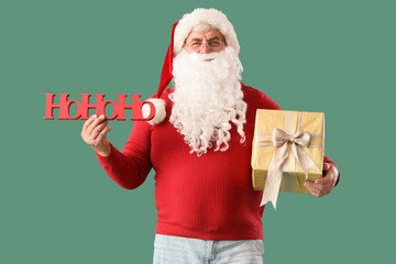 Santa Claus with word HOHOHO and gift box on green background. Christmas celebration