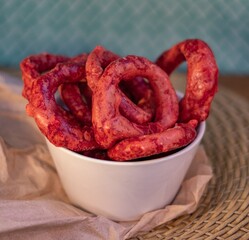 Crispy onion rings with red chili seasoning served in a white bowl, perfect for snack or appetizer imagery.