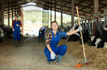Obraz premium Woman is employee of company during break in work. She stands next to animal pen, with rural hilly landscape in background.