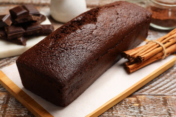 Tasty chocolate sponge cake and ingredients on wooden table, closeup