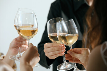 People clinking glasses of wine indoors, closeup