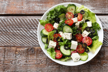 Delicious salad with feta cheese on wooden table, top view. Space for text
