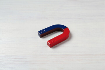 One horseshoe magnet on white wooden table