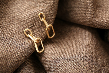 Beautiful golden earrings on fabric background, closeup