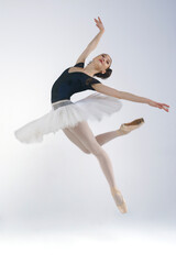 Naklejka premium young ballerina in a white tutu on a white background jumps bent over. Beautiful ballerina