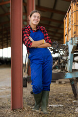 Young woman in overalls posing while working on farm