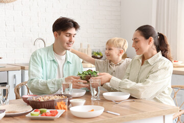 Parents with their little son eating Fajita at table in kitchen