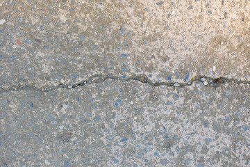 A crack in the pavement with gravel and rocks in it