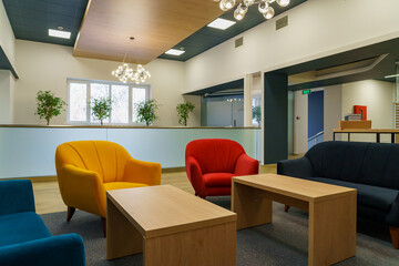 Modern lounge area with colorful seating, wooden tables, and greenery