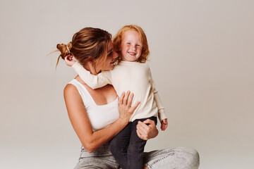 Mother and daughter bonding on the floor in front of a blank white wall during a photo shoot