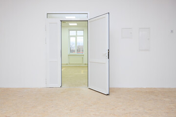 Open doorway leading to a newly renovated room with white walls and large windows