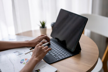 Fototapeta premium Businesswoman analyzing charts and typing on tablet at home office