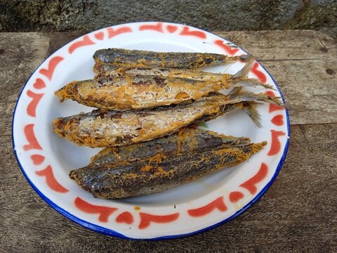 Delicious fried salted fish or ikan pindang in a plate on wooden table. 