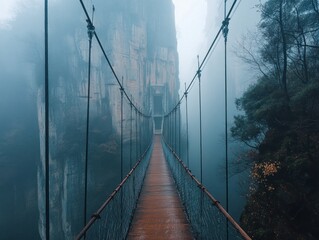 Obraz premium A misty suspension bridge connecting cliffs in a serene, atmospheric landscape.