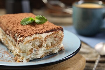 Piece of tasty tiramisu on wooden table, closeup