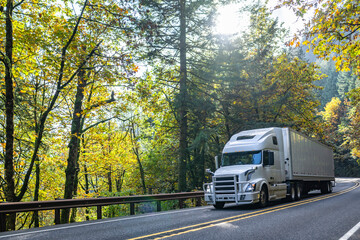 Popular white big rig semi truck with grille guard transporting cargo in dry van semi trailer...