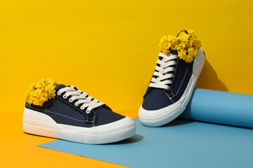 Stylish sneakers with flowers on a yellow background