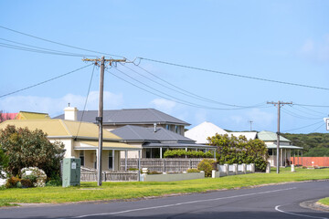 Australian suburban street with a row of residential house and power lines along a country road....