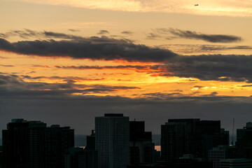 Vivid dark sky with dark clouds and golden hues in between over Puget Sound; high above is an...