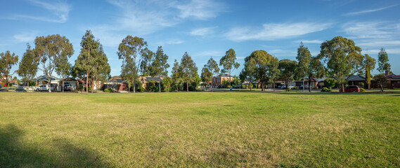 Panoramic of large open space with green grass lawn with some residential houses in the background....