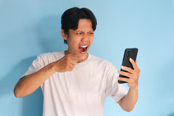 Angry young Asian man pointing at his mobile phone