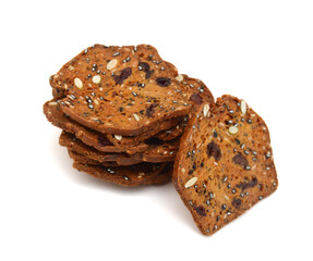 Baked crisps with cranberries, nuts and seeds stacked on a white background