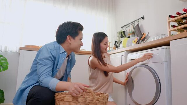 Attractive couple put dirty clothes to washing machine in house together.