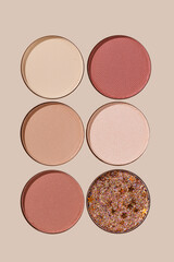 Set of shimmer and matte eyeshadow refills, beige, brown, red, pink, purple colored shades, objects on beige background. Top view of Swatches Eyeshade  makeup for cosmetic, makeup, beauty