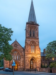 Obraz premium A historic church building illuminated at dusk, showcasing intricate architecture.