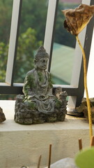 Stone Buddha Statue on Windowsill with Green Plants