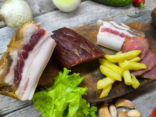 Dried meat on a cutting board surrounded by vegetables.