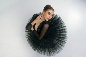 portrait of a young ballerina in a black tutu dancing with her hands moving top view, immersion in...