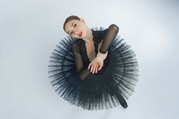 portrait of a young ballerina in a black tutu dancing with her hands moving top view, immersion in dance