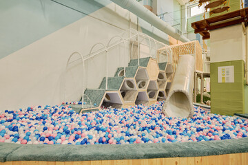 Corner of spacious modern playground with many multi color balloons, pipe tunnel and staircase with side net
