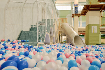 Abundance of multi color balloons, pipe tunnel and staircase with side net along wall of spacious...