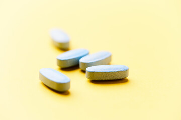 Multivitamin tablets on bright paper background. Close up. Copy space	