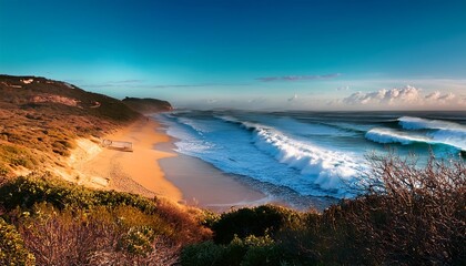 Fototapeta premium Beachscape with golden sand, turquoise waves lapping the shore, and a vibrant blue sky