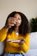Vertical portrait of young Black woman using pendulum at home. Divination tool for spiritual...